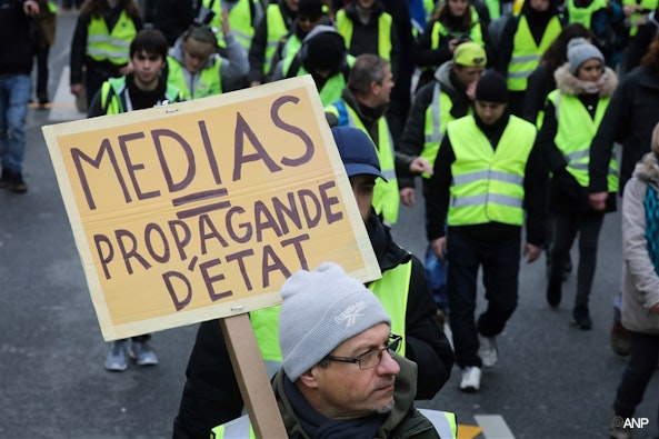 A demonstrator holds a placard reading "Medias equal State propaganda", during an anti-government demonstration called by the Yellow Vest "Gilets Jaunes" movement, on January 12, 2019, in Paris. France braced for a fresh round of "yellow vest" protests across the country on with the authorities vowing zero tolerance for violence after weekly scenes of rioting and vandalism in Paris and other cities over the past two months. ludovic MARIN / AFP