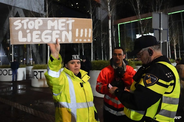 A police officer checks the ID of a protestor holding a sign which reads "Stop Lying" during a small demonstration against COVID-19 restrictions outside a ministry building where caretaker Prime Minister Mark Rutte and caretaker Health Minister Hugo de Jonge announced an extension of the partial lockdown in The Hague, Netherlands, Friday, Nov. 26, 2021. (AP Photo/Peter Dejong)